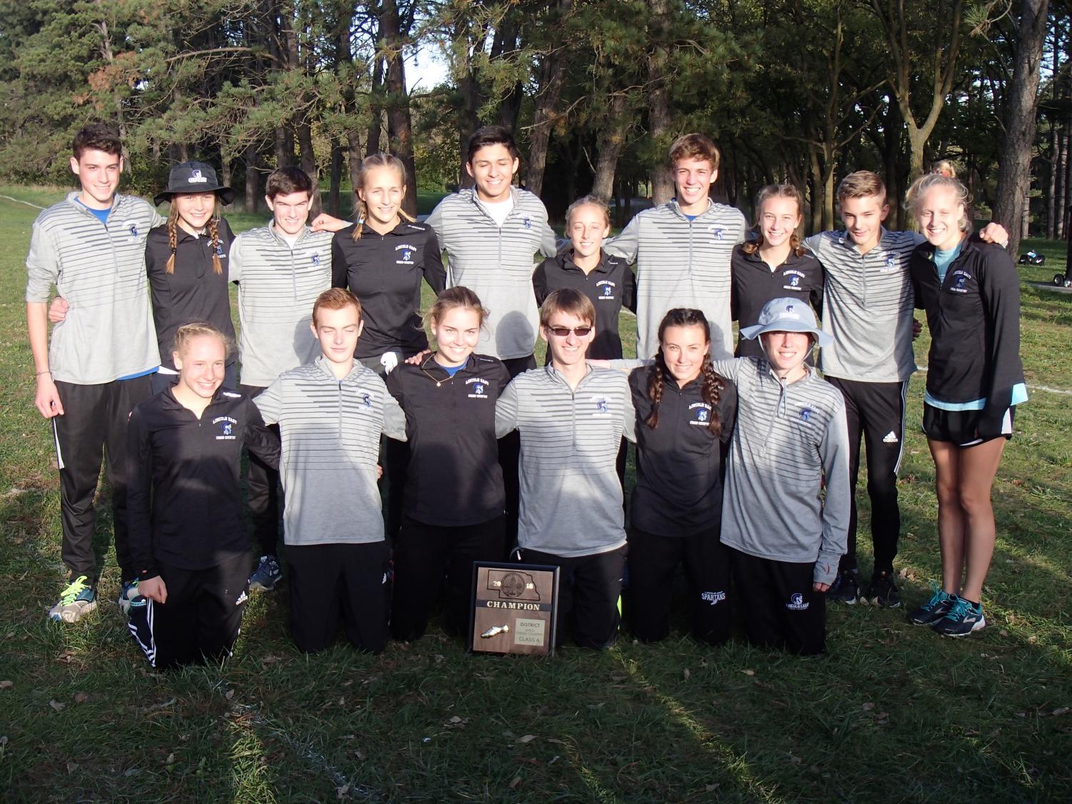 The East varsity runners smile with their district champions' plaque, after a successful district meet for the boys and girls alike.