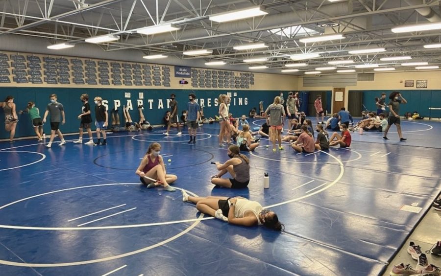 Lincoln East cross country team stretching after practice on Friday, September 3rd. Due to covid 19 athletes are required to wear masks at all times while in the building.