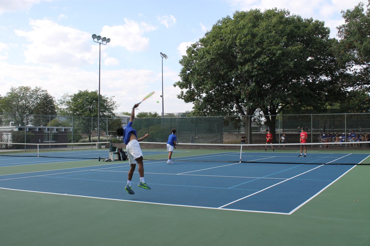 Sophmore Samarth Sajeesh (left)  with his Dual Partner, senior Caden Haar at Woods Tennis Center, on September 13th 2023. Sajeesh serves the ball to the LHS players while Haar moves up to the net, preparing for when they return the ball.
