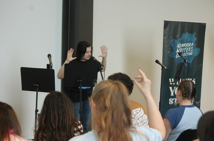 Alex Hamric performs their poem "Fascism is a Business Major" at the All Writes Reserved festival semifinals in Omaha, NE. Spectators snapped and cheers for Hamric's perfectly-scored performance.